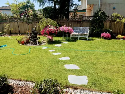 a backyard with a garden with a garden hose on the grass at Great Guest Suite in a Gorgeous House in New Westminster