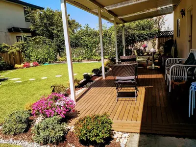 a wooden deck with chairs and flowers in a yard at Great Guest Suite in a Gorgeous House in New Westminster