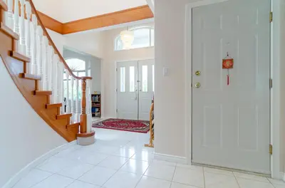a hallway with white walls and a staircase with white tile floors at Great Guest Suite in a Gorgeous House in New Westminster