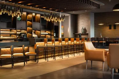 a restaurant with a bar with brown chairs and tables at Hyatt Place Calgary Airport in Calgary