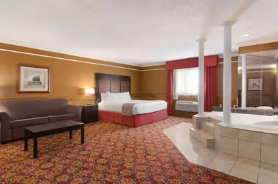 a hotel room with a bed and a tub at Travelodge by Wyndham Meadow Lake in Meadow Lake