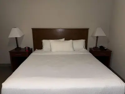 a bedroom with a large white bed with two lamps at Super 8 by Wyndham Fort St. John BC in Fort Saint John