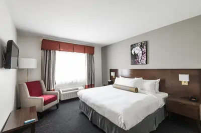 a hotel room with a large bed and a chair at Edgewater Hotel in Whitehorse