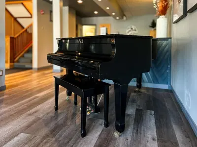 a black piano in a room with a staircase at Edgewater Hotel in Whitehorse