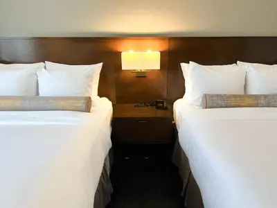 two beds in a hotel room with white pillows at Edgewater Hotel in Whitehorse