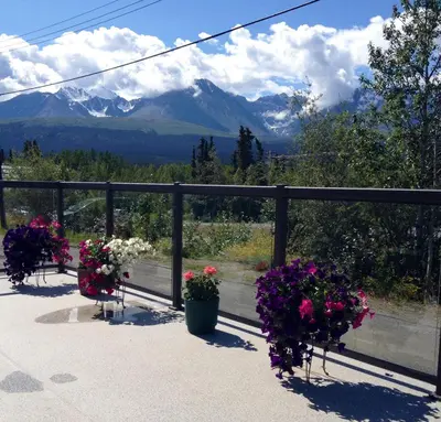 a balcony with flowers and a view of mountains at Parkside Inn in Haines Junction