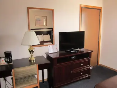 a hotel room with a desk and a television on a dresser at Super 8 by Wyndham Williams Lake BC in Williams Lake