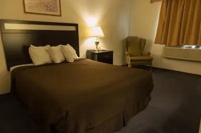a hotel room with a large bed and a chair at Super 8 by Wyndham Williams Lake BC in Williams Lake