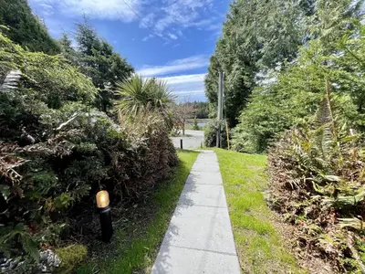 a sidewalk in a garden with bushes and trees at Waterfront Hot Tub Firepit King Bed - 6H in Ucluelet