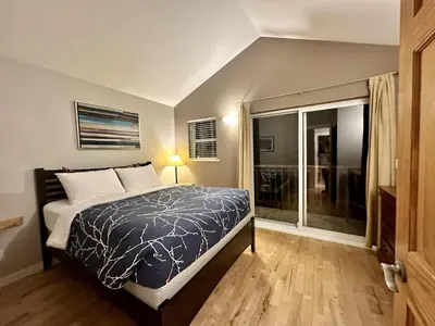 a bedroom with a bed and a large window at Cozy 2 Bedroom Waterfront Cottage With Hot Tub! in Ucluelet