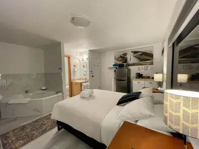 a bedroom with a large bed and a bath tub at Waterfront Private Room With Hot Tub & Firepit in Ucluelet