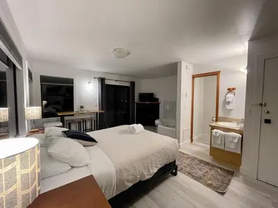 a bedroom with a large bed and a bathroom at Waterfront Private Room With Hot Tub & Firepit in Ucluelet