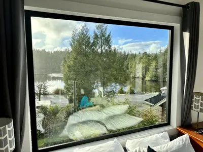 a large window with a view of a lake at Waterfront Private Room With Hot Tub & Firepit in Ucluelet