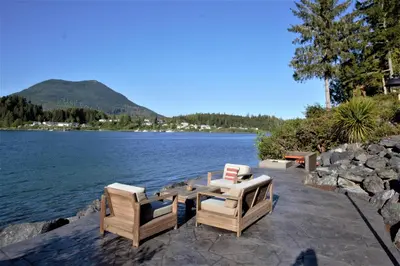 a table and two chairs sitting next to a lake at Waterfront Private Room With Hot Tub & Firepit in Ucluelet