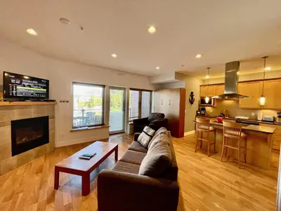 a living room with a couch and a table and a kitchen at Marina View On The Harbour in Ucluelet