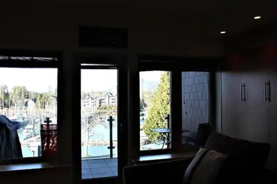 a room with three windows with a view of a harbor at Marina View On The Harbour in Ucluelet