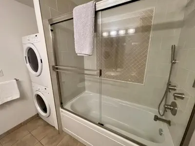 a bathroom with a shower and a washing machine at Marina View On The Harbour in Ucluelet