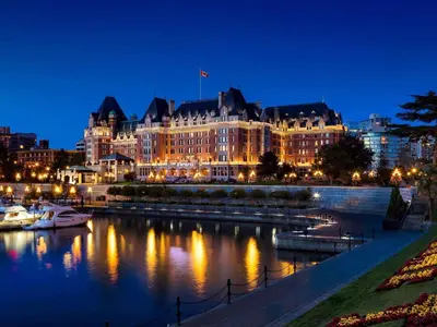 a large building with lights on the water at night at Fairmont Empress Hotel in Victoria