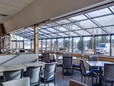 a restaurant with tables and chairs and windows at Heritage Inn Hotel & Convention Centre - High River in High River