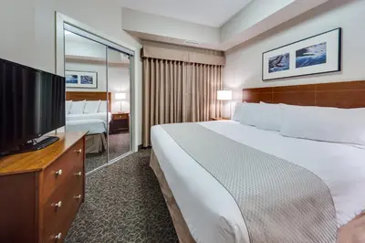 a hotel room with a large bed and a flat screen tv at Heritage Inn & Suites - Brooks in Brooks