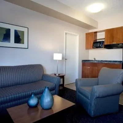 a living room with a couch and a chair and a table at Heritage Inn & Suites - Brooks in Brooks