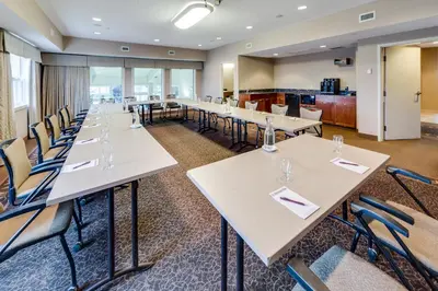 a row of tables and chairs in a room with windows at Heritage Inn & Suites - Brooks in Brooks