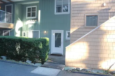 a house with a stairway leading to a white door at Siennas Harbour House in Tofino