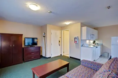a living room with a couch and a table and a kitchen at Travelodge by Wyndham Nanaimo in Nanaimo