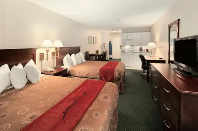 a hotel room with two beds and a flat screen tv at Travelodge by Wyndham Nanaimo in Nanaimo