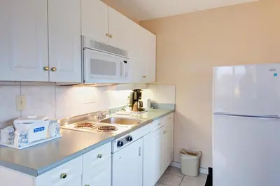 a kitchen with white cabinets and a white refrigerator at Travelodge by Wyndham Nanaimo in Nanaimo