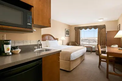 a hotel room with a bed and a kitchen with a sink at Super 8 by Wyndham High Level AB in High Level