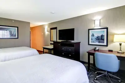 a hotel room with two beds and a desk and a television at Hampton Inn & Suites by Hilton Calgary-Airport in Calgary