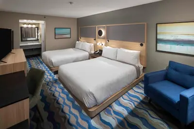 a hotel room with two beds and a blue chair at Accent Inns Kelowna in Kelowna