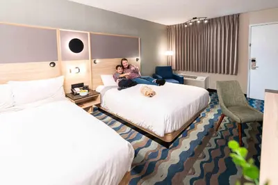 a woman sitting on a bed in a hotel room at Accent Inns Kelowna in Kelowna