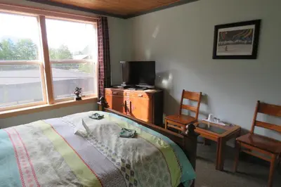 a bedroom with a bed and a tv and a chair at Historic Hotel Bayview in Stewart