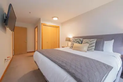 a bedroom with a large bed and a flat screen tv at Glaciers Lodge by Outpost Whistler in Whistler