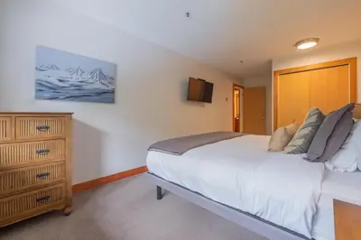 a bedroom with a large bed and a dresser at Glaciers Lodge by Outpost Whistler in Whistler