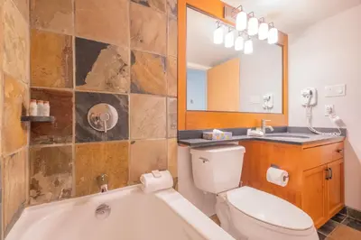 a bathroom with a tub and a toilet and a sink at Glaciers Lodge by Outpost Whistler in Whistler