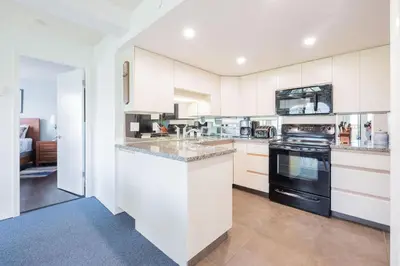a kitchen with white cabinets and black appliances at Marquise by Outpost Whistler in Whistler