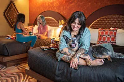 a woman sitting on a bed with a dog at Hotel Zed Victoria in Victoria