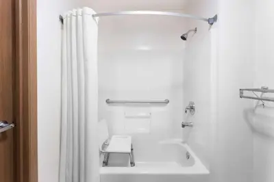 a white bathroom with a white shower curtain and a toilet at Super 8 by Wyndham Yellowknife in Yellowknife
