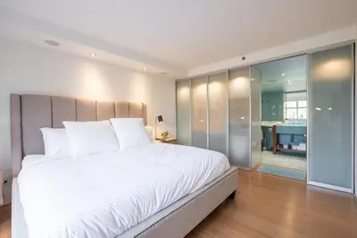 a bedroom with a large white bed and a bathroom at Woodrun by Outpost Whistler in Whistler