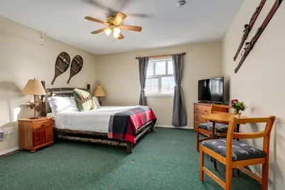 a bedroom with a bed and a television and a chair at Courthouse Inn Revelstoke in Revelstoke