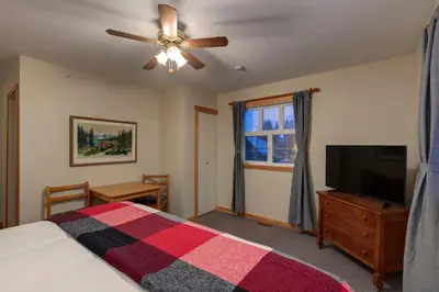 a bedroom with a bed and a flat screen tv at Courthouse Inn Revelstoke in Revelstoke