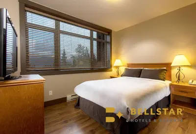 a bedroom with a large bed and a large window at Palliser Lodge — Bellstar Hotels & Resorts in Golden
