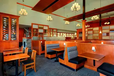 a restaurant with wooden tables and chairs and a bar at Four Points by Sheraton Edmonton Gateway in Edmonton