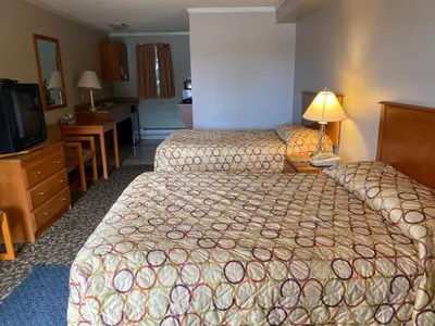 a hotel room with two beds and a television at Aspen Motor Inn in Drayton Valley