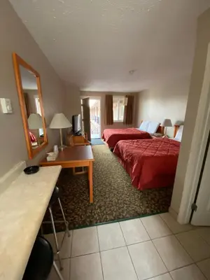 a hotel room with two beds and a desk and a mirror at Aspen Motor Inn in Drayton Valley