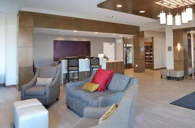a lobby with a couch and chairs and a piano at Staybridge Suites - Red Deer North by IHG in Red Deer