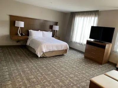 a hotel room with a bed and a flat screen tv at Staybridge Suites - Red Deer North by IHG in Red Deer